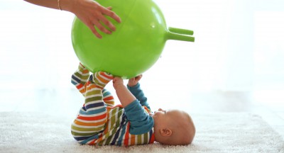 Baby playing with gymnastic ball with mother at home