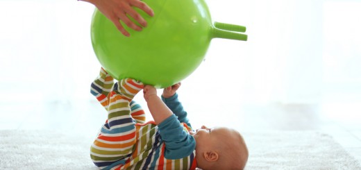 Baby playing with gymnastic ball with mother at home